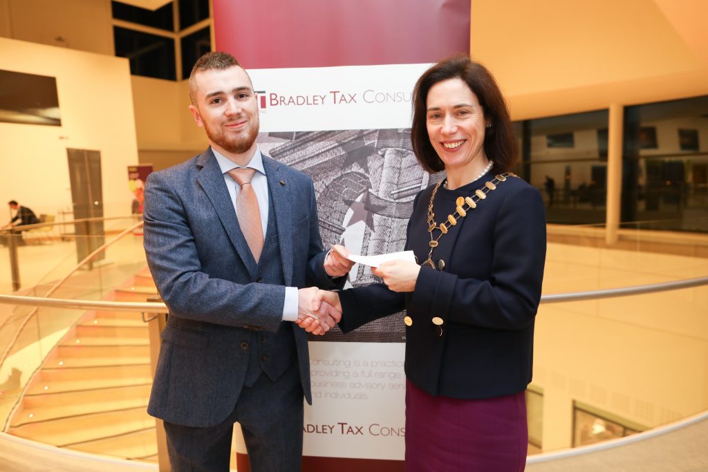 Aidan Toomey receiving the prize for Joint Highest Marks at Part 2 Personal Taxes Exam from Marie Bradley, Institute President and Managing Director, Bradley Tax Consulting.